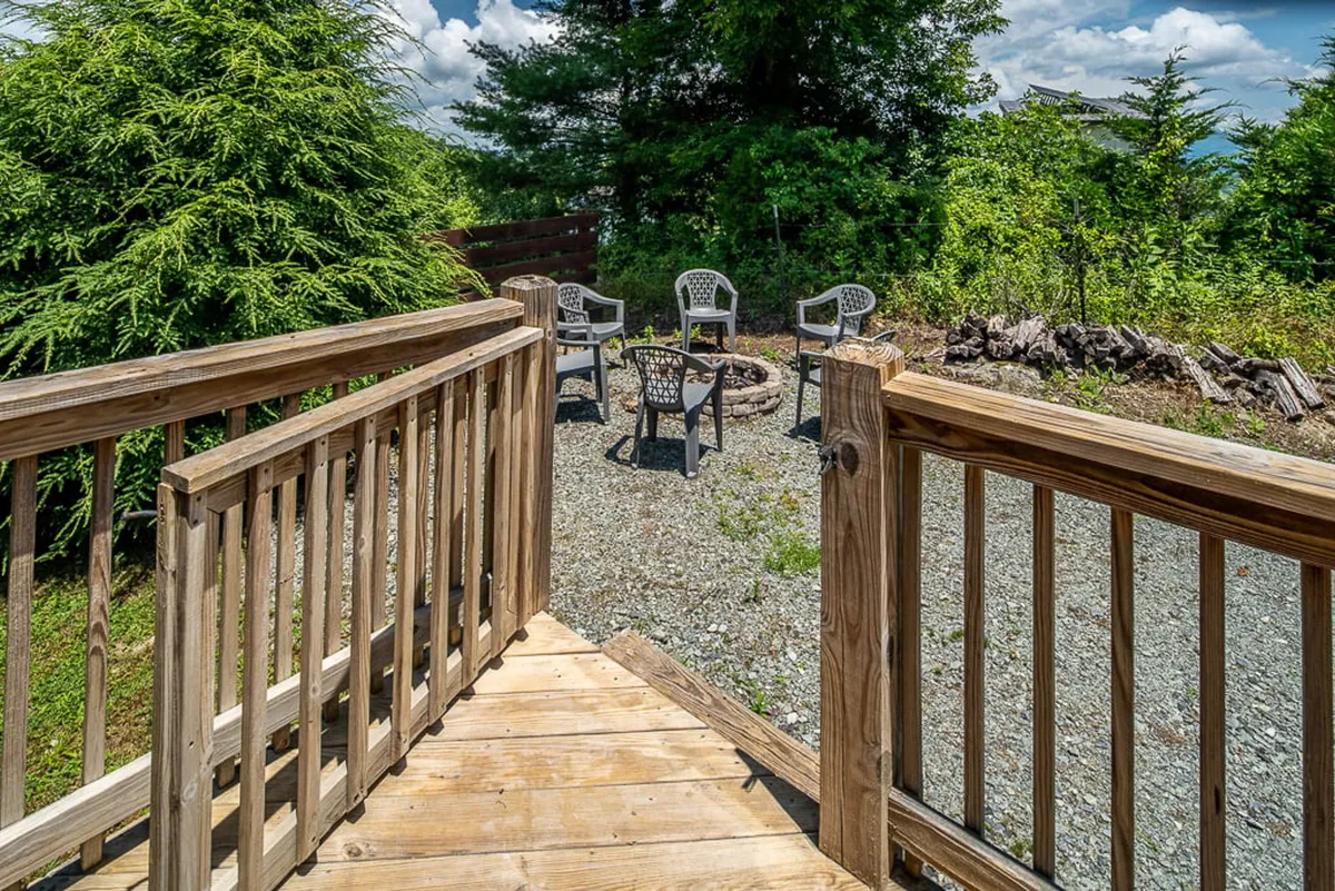 A cozy fire pit is the centerpiece of this deck, surrounded by comfortable seating and greenery. The arrangement is ideal for evening gatherings, s’mores, and stargazing, making it a welcoming hub for stories and laughter under the open sky.