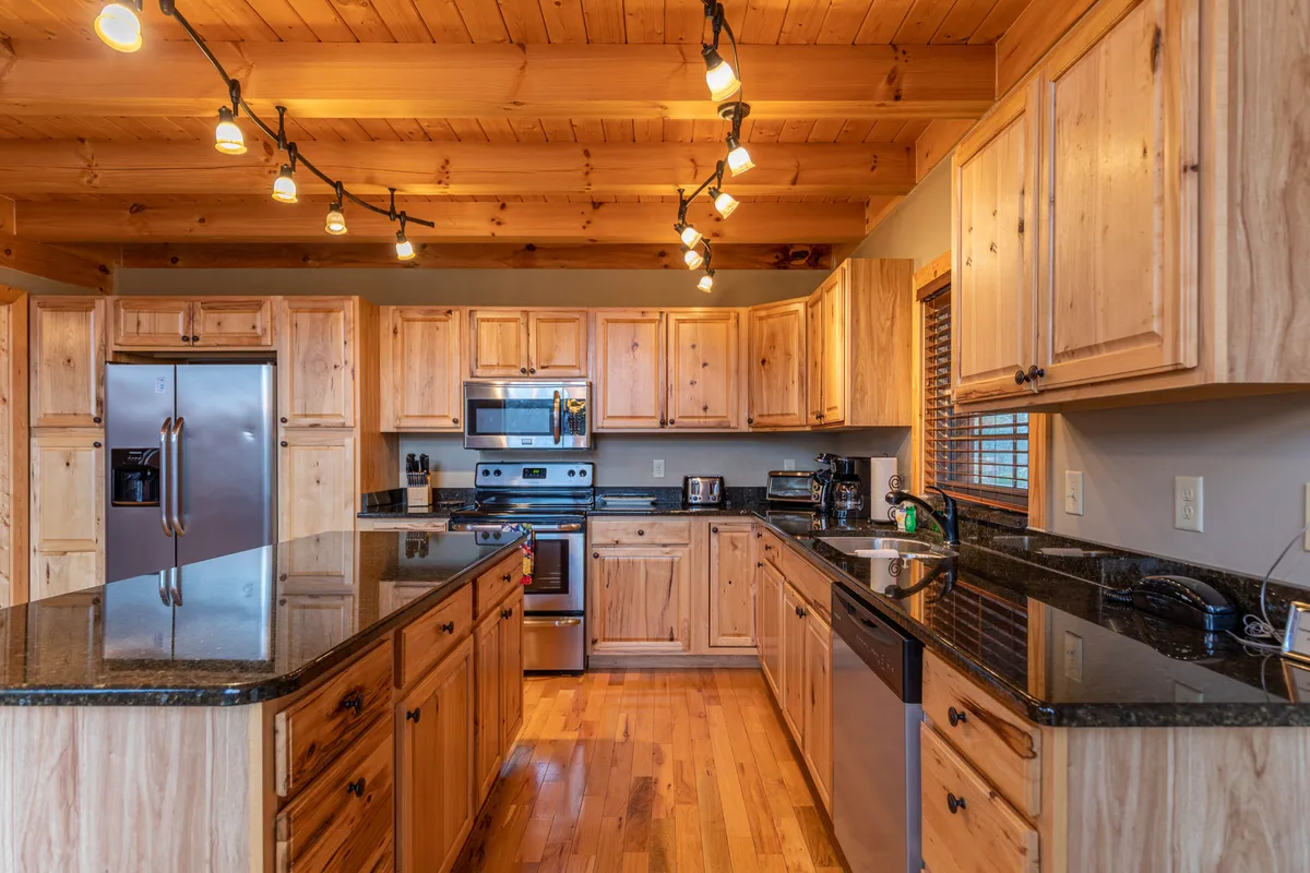A bright, modern kitchen with a large island, stainless steel appliances, wooden cabinetry, and granite countertops. The space is designed for cooking and conversation, with ample room for families to gather, prepare meals, and connect.